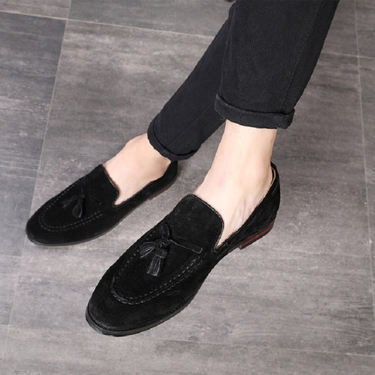 Men's suede tassel slip-on loafers in black, shown on feet with low-profile sole