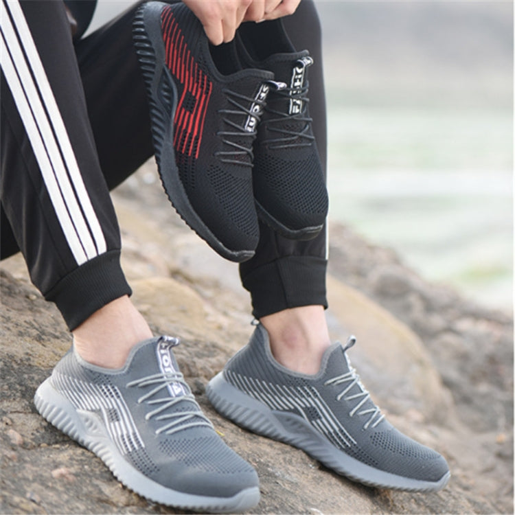 Grey men’s work sneakers worn with black pants, showing lace-up upper and tread sole