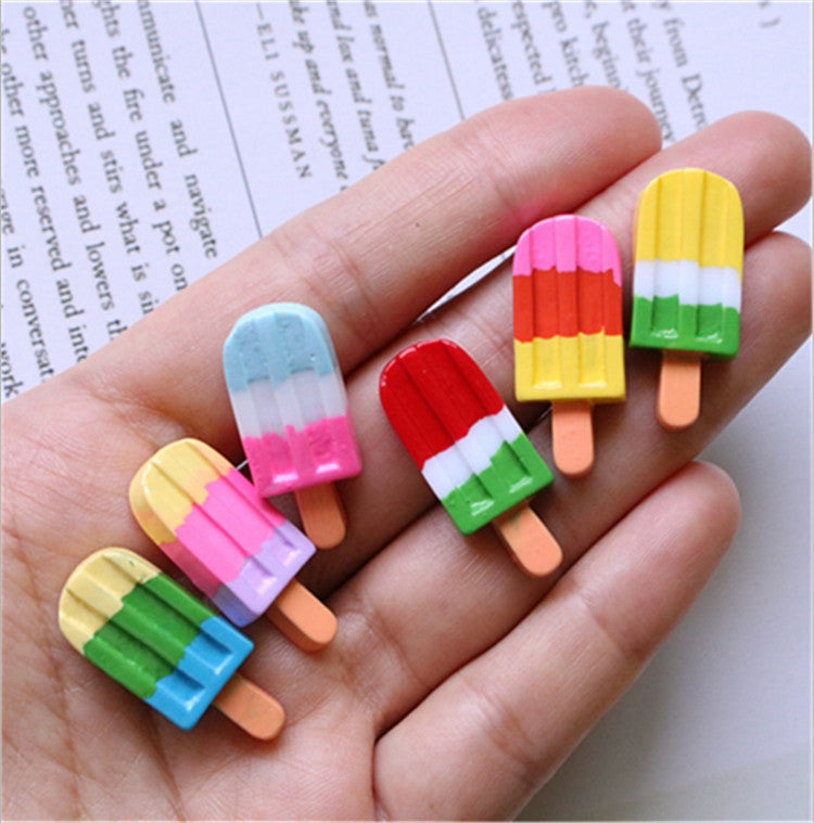 Ice cream stick resin cabochons in hand: yellow, pink, red and green striped