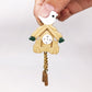 Mini wooden birdhouse clock held in hand; white bird top, round face, gold chain weights