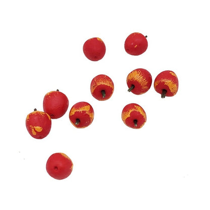 Miniature red apple fruit pieces with stems, scattered on a white surface.