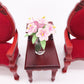 Mini dollhouse lily bouquet in clear glass vase between red miniature chairs