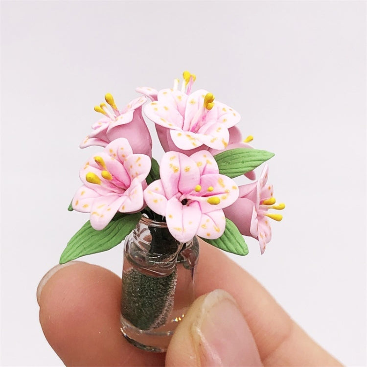 Mini dollhouse lily bouquet with pink petals and green leaves in clear vase