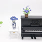 Purple rose flower model toy in brown pot on miniature black piano