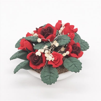 Miniature potted rose bouquet with red roses, green leaves, and white berry accents in white pot