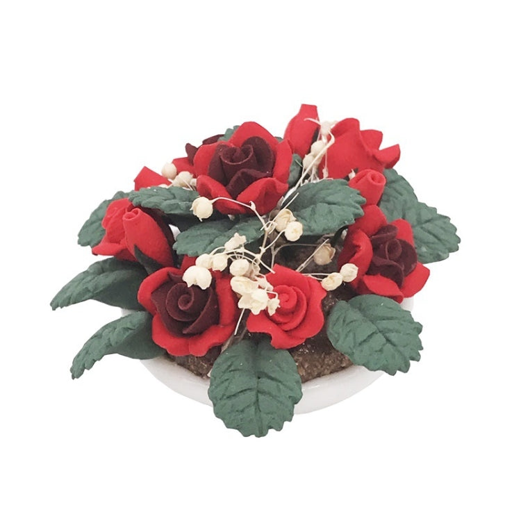 Miniature potted rose bouquet with red roses and green leaves in a white planter