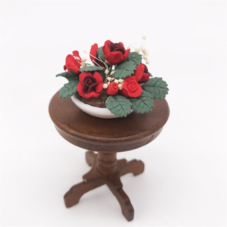 Miniature potted rose bouquet on a small brown pedestal stand with red roses and green leaves