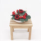 Miniature potted rose bouquet with red roses on a wooden bench
