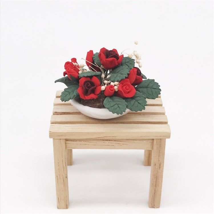 Miniature potted rose bouquet with red roses on a wooden bench