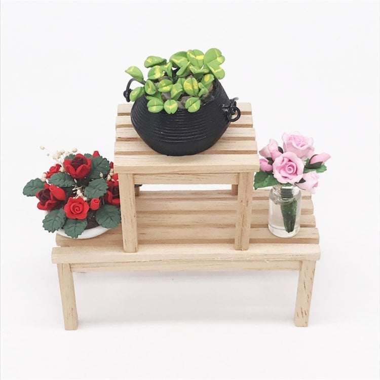 Miniature flower pots on a wooden bench: green roses in black pot and pink roses in jar