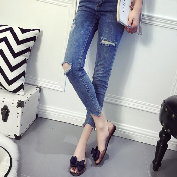 Transparent jelly flats with dark bow accents and open toe worn with jeans