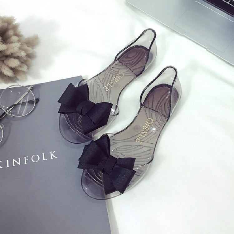 Transparent jellyfish-mouth flat shoes with large dark bows and curved clear sole
