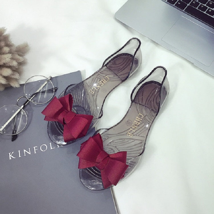Pair of transparent jelly shoes with dark red bow and open-toe design
