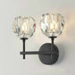Black double wall sconce with two faceted crystal shades and round backplates