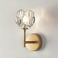 Gold wall lamp with faceted crystal shade and round wall plate