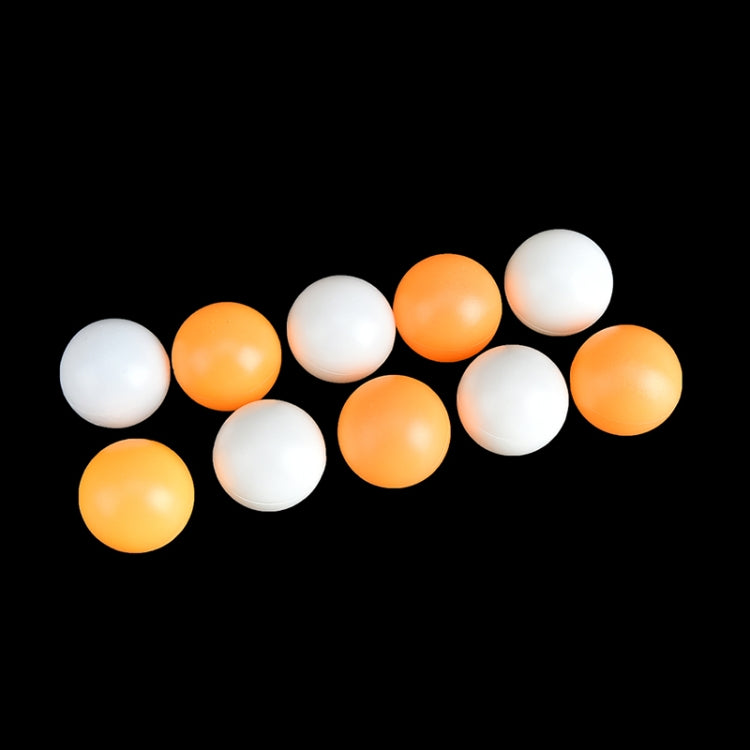 Seamed table tennis balls, orange and white, scattered on dark background