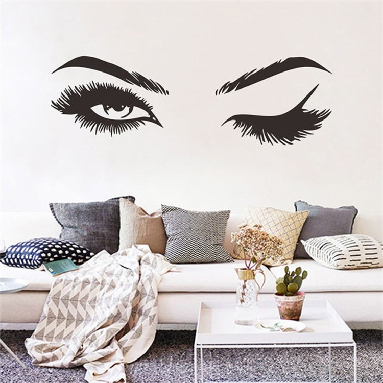 Black eye-and-eyebrow wall sticker set displayed above a living room sofa.