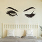 Black eye and eyebrow wall decals above a bed headboard.