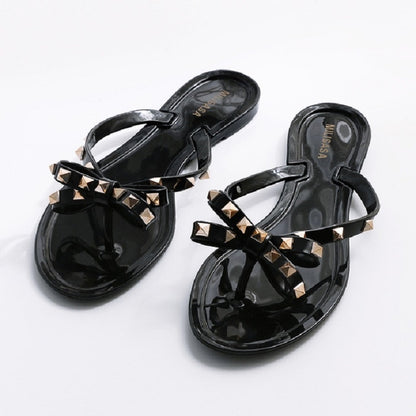 Black flip-flops with rhinestone-studded bow straps and thong-style flat sole