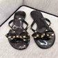 Black flat thong sandals with rhinestone bow detail across the straps