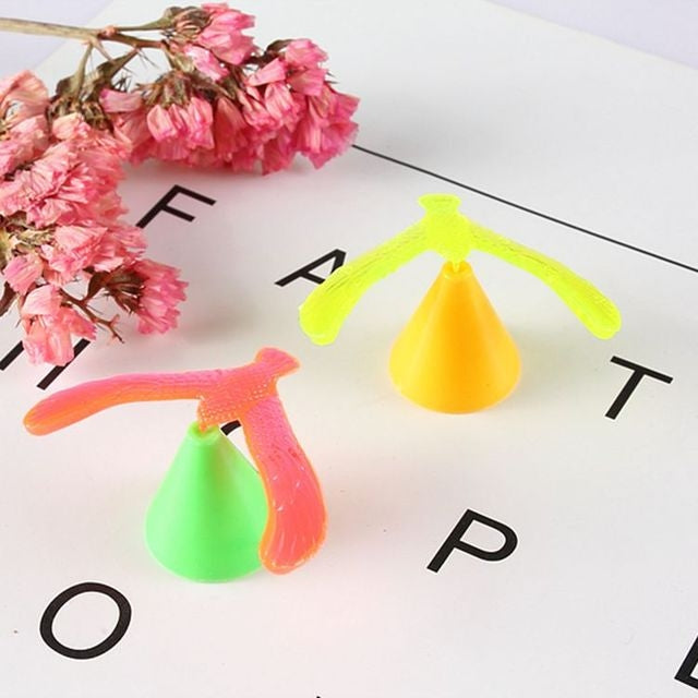 Colorful balancing bird toy with neon green, orange, and yellow parts on cards