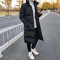 Men's black long puffer down coat with high collar, button closure, standing front