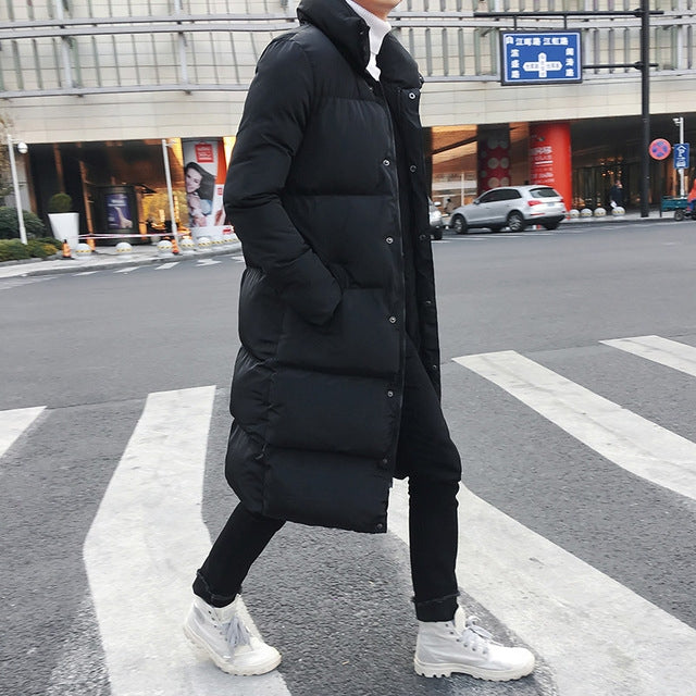 Men's black long puffer down jacket, button front, quilted insulation, standing side view