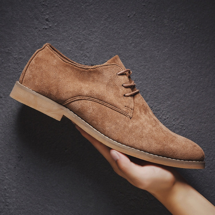 Men's brown suede oxford shoes with lace-up front and light sole, held in hand