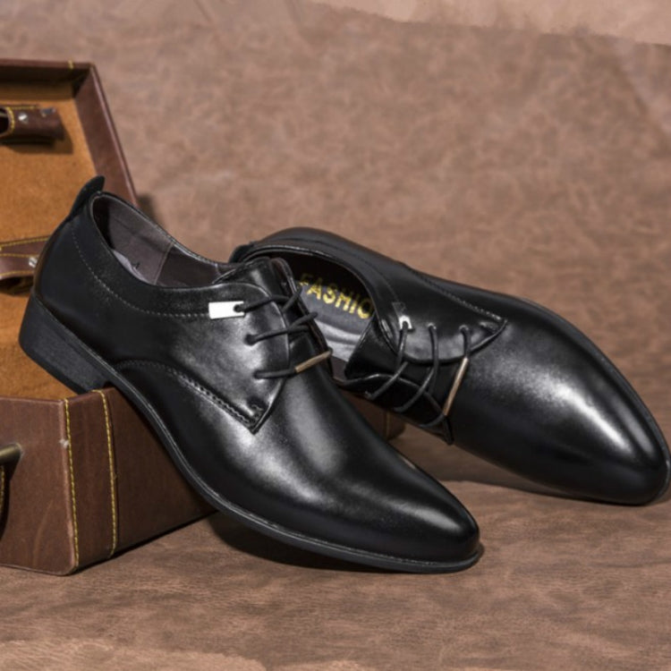 Black pointed-toe lace-up dress shoes shown at angle on a tabletop