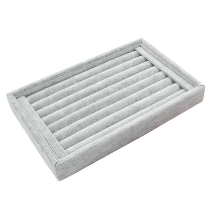 Gray velvet jewelry storage tray with slotted divider rows for rings and earrings