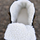 Interior view of white sherpa lining at the top of a black snow boot