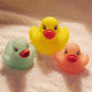 3 pastel rubber duck bath toys with cute faces resting on a towel