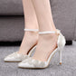 White stiletto heels with pointed toe, rhinestone floral appliques, and ankle strap