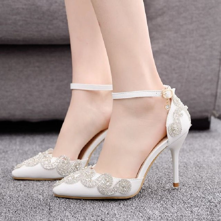White stiletto heels with pointed toe, rhinestone floral appliques, and ankle strap