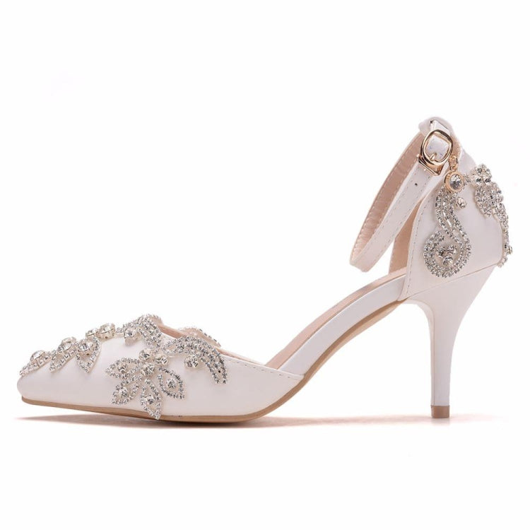 White pointed-toe stiletto heels with rhinestone floral embellishment and ankle buckle