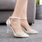 White stiletto heels with pointed toe, rhinestone embellishment, and ankle strap closure