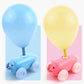 Close-up of blue and pink pig balloon cars with balloons and small friction cars