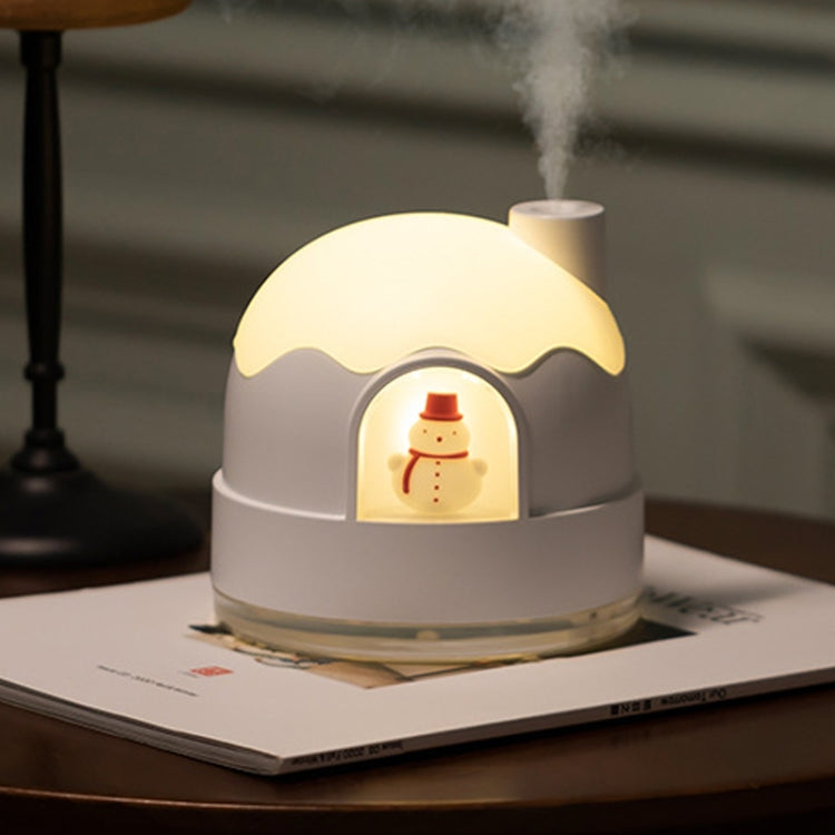 White snowman humidifier night light emitting mist, warm yellow glow from front.