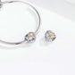Heart-shaped charm bead beside a silver snake bracelet clasp; rose gold clover center visible.