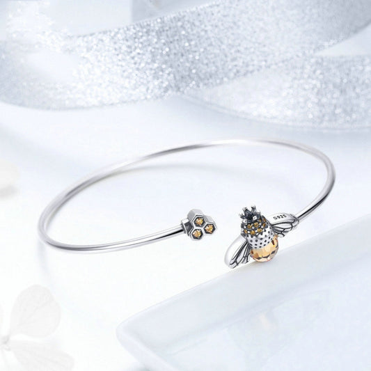 Sterling silver bangle bracelet featuring bee charm with faceted yellow bead