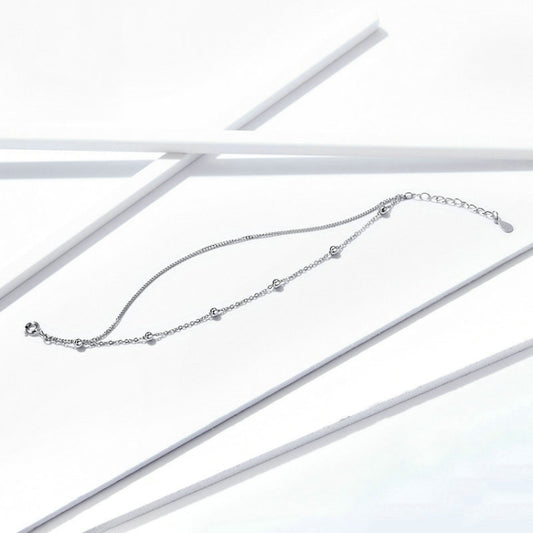 Silver chain bracelet with small round charm accents, laid flat with clasp at one end.