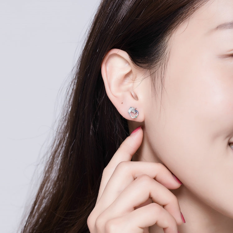 Silver stud earrings with heart-shaped zircon accent on a model's ear
