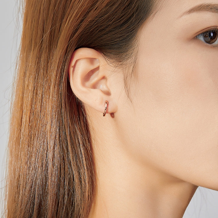 Rose gold hoop earrings worn on ear with hinged clasp, small circular shape