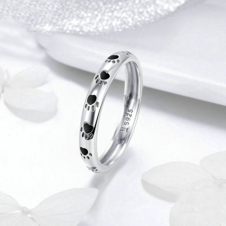 Sterling silver ring with black paw print details along the front band, side view