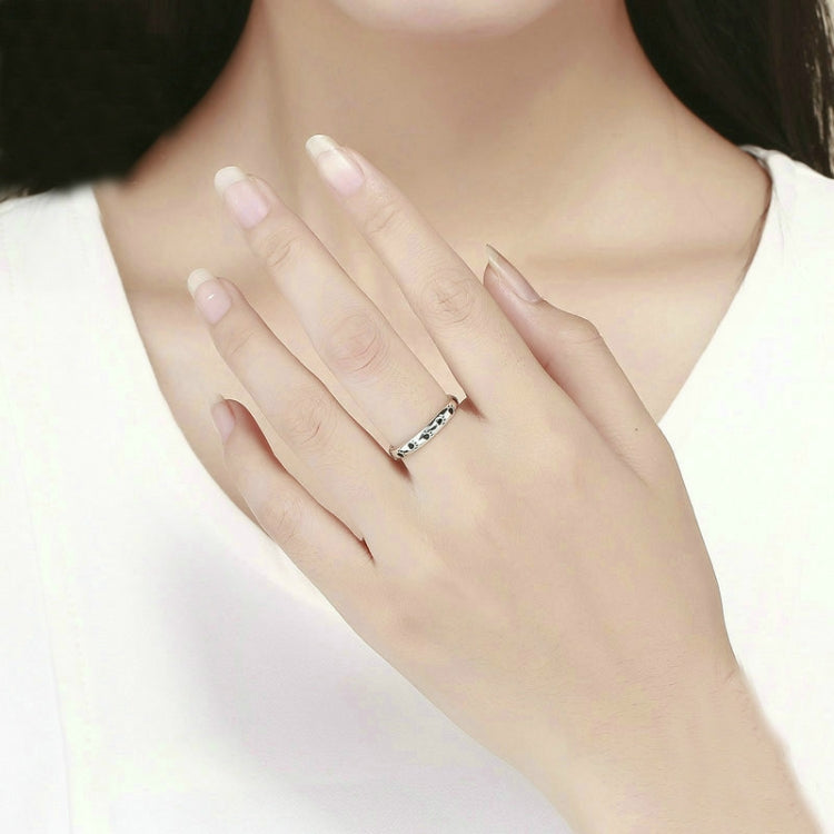Sterling silver paw print ring on finger with black enamel footprint accents