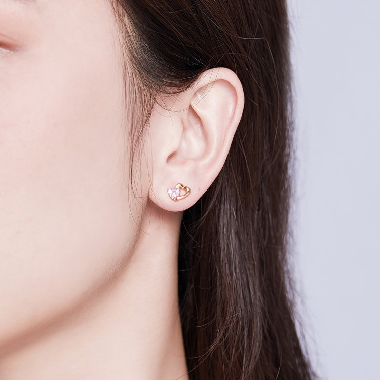 Heart stud earrings on ear: rose gold finish with pink heart CZ