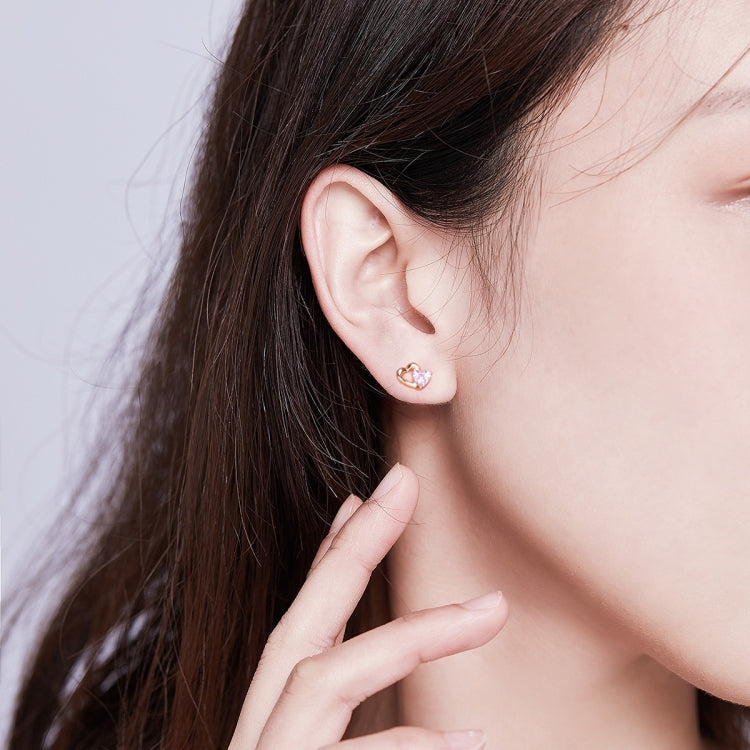 Close view of rose gold heart stud earrings with pink heart CZ on model ear