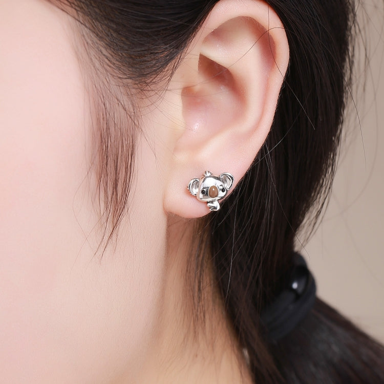 Koala stud earrings worn on an ear, polished silver with brown enamel koala face