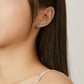 Silver ribbed feather earrings worn on ear, etched feather design
