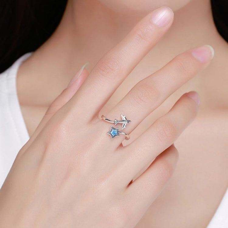 Sterling silver open ring on finger with star design and blue center stone